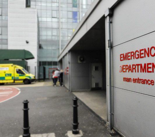 Emergency department entrance with image of ambulance and 3 people in the background